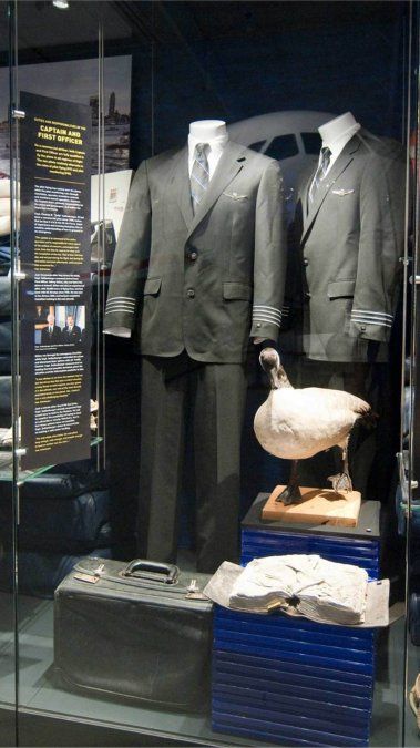 Los uniformes de Sullenberger (izquierda) y Skiles, junto con un maletín de vuelo y un manual de la aeronave, junto con un ganso de Canadá embalsamado, son exhibidos en el Carolinas Aviation Museum.
