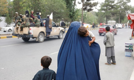 Una mujer afgana camina con sus hijos en el aniversario de la caída de Kabul en una calle de Kabul, Afganistán, 15 de agosto de 2022. Una mujer afgana camina con sus hijos en el aniversario de la caída de Kabul en una calle de Kabul, Afganistán, 15 de agosto de 2022.