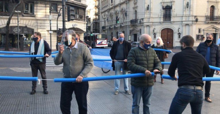 Imágenes de la protesta contra la reforma judicial del 17A del año pasado, donde se ve al actor y al exfuncionario Hernán Lombardi sosteniendo -cada uno desde un extremo- un flota-flota, de modo tal de preservar el distanciamiento social.