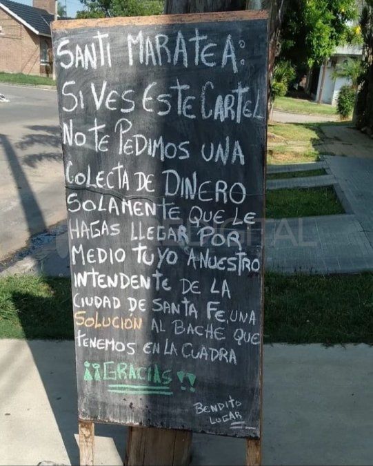 El cartel para Santi Maratea en el que le piden ayudar para que la Municipalidad de Santa Fe les arregle el bache. 