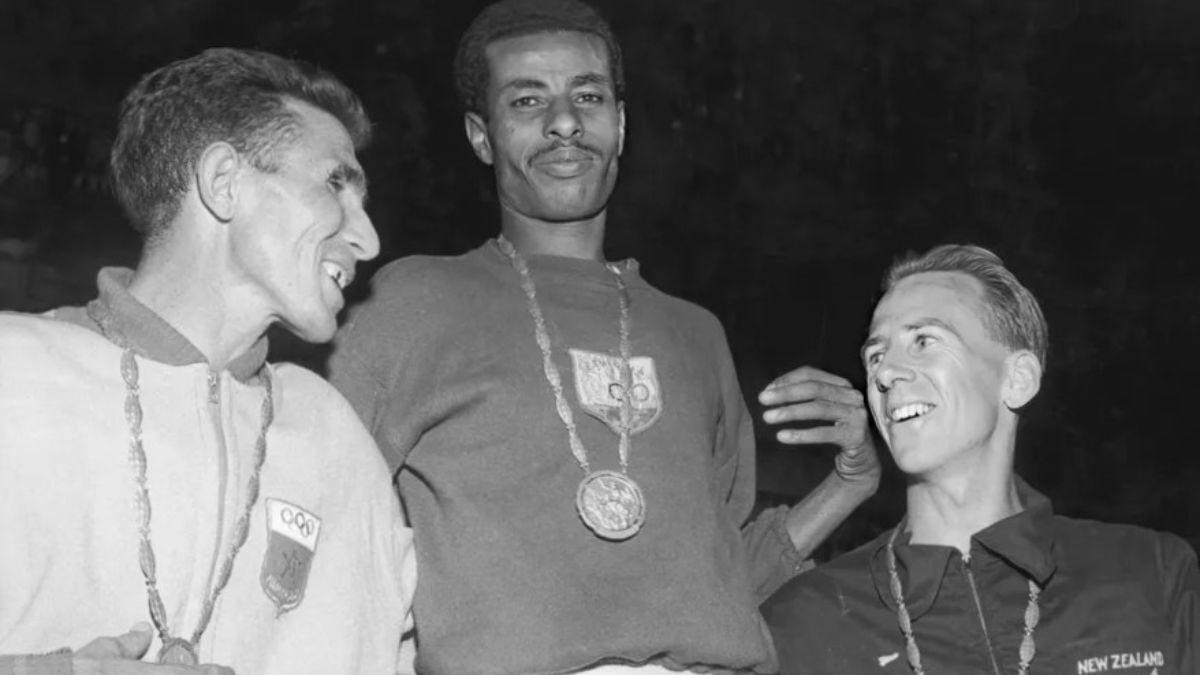 El podio del maratón de Roma 1960: Bikila, en lo más alto, junto con el marroquí Rhadi Ben Abdesselam (a su derecha), que logró la medalla de plata, y el neozelandés Barry Magee, que obtuvo la presea de bronce. El podio del maratón de Roma 1960: Bikila, en lo más alto, junto con el marroquí Rhadi Ben Abdesselam (a su derecha), que logró la medalla de plata, y el neozelandés Barry Magee, que obtuvo la presea de bronce.