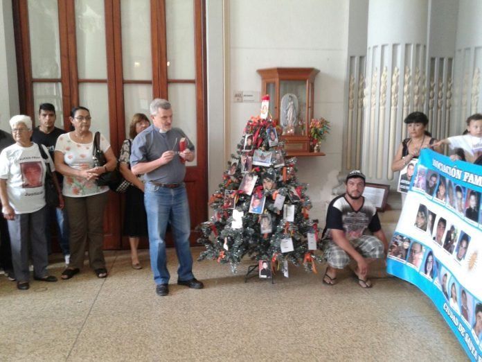 El Árbol de la Memoria plantado en Casa de Gobierno en el año 2014. Entre sus ramas sostiene las fotos y los nombres de santafesinos inocentes que murieron víctimas de la inseguridad. En la foto: el padre Axel Arguinchona en apoyo espiritual a los familiares, Catalina de Narváez y Graciela Brondino junto a demás integrantes de la Asociación de familiares de víctimas