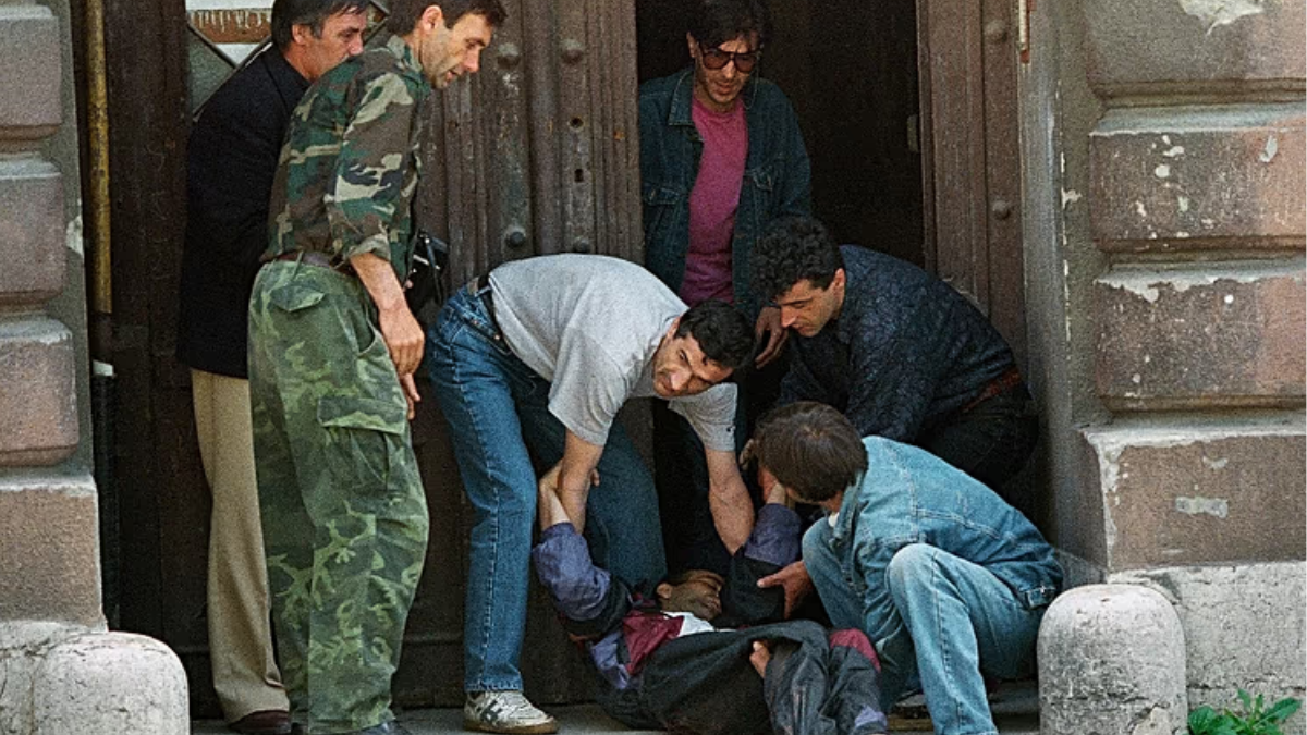 Un hombre sangrante alcanzado por un francotirador fue arrastrado a la seguridad de un portal el 14 de junio de 1995. AP PhotoJerome Delay