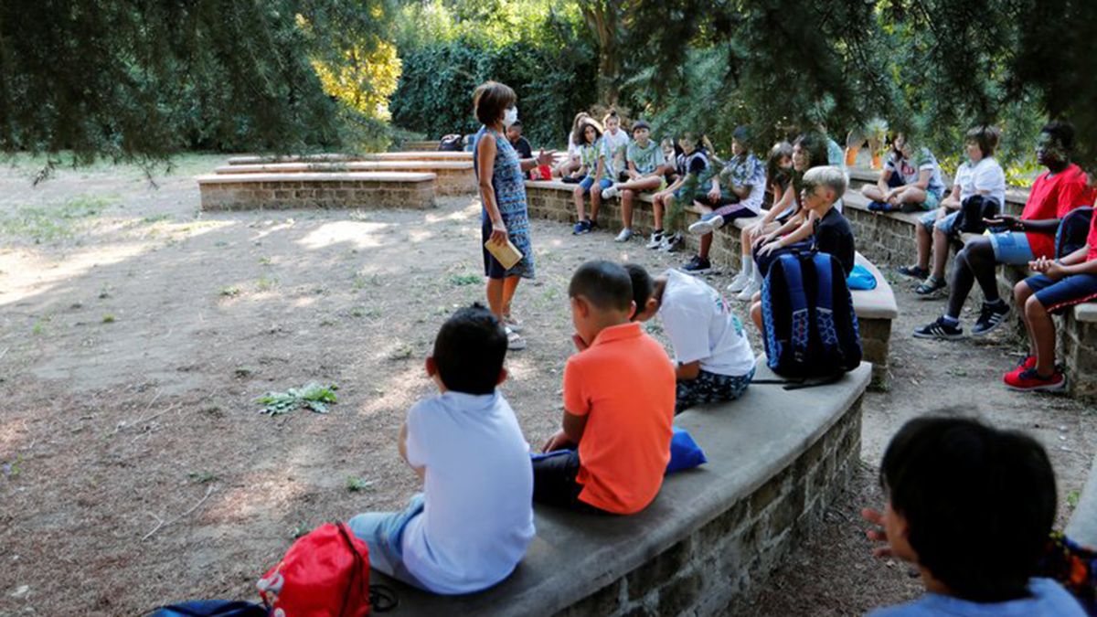 En Italia, una maestra dicta una clase al aire libre a alumnos más pequeños. El país inició el ciclo lectivo entre el 14 y el 24 de septiembre.