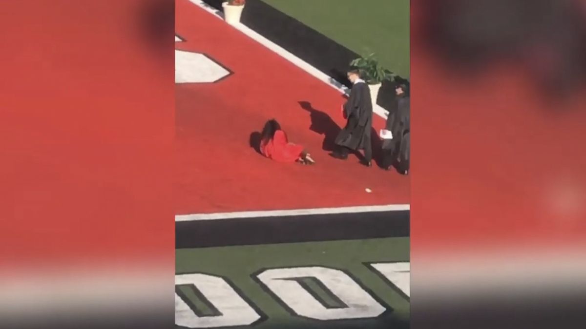 La joven en tacones pierde el equilibrio mientras camina hacia el escenario y termina cayendo al suelo