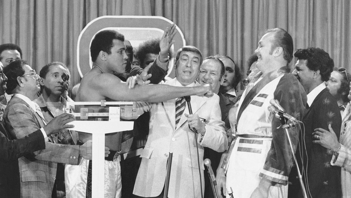 Muhammad Ali (izquierda), quien venía de recuperar sus coronas ante George Foreman en Kinshasa, Zaire, pesó 101,400 kilos y, Wepner, 102,100. El campeón, de 1,88 metro, pronosticó que la pelea con Chuck, que era 8 centímetros más alto, sería un “entrenamiento público”. En el centro está el reconocido periodista Howard Cosell, quien los entrevistó luego de que subieran a la báscula. Muhammad Ali (izquierda), quien venía de recuperar sus coronas ante George Foreman en Kinshasa, Zaire, pesó 101,400 kilos y, Wepner, 102,100. El campeón, de 1,88 metro, pronosticó que la pelea con Chuck, que era 8 centímetros más alto, sería un “entrenamiento público”. En el centro está el reconocido periodista Howard Cosell, quien los entrevistó luego de que subieran a la báscula.